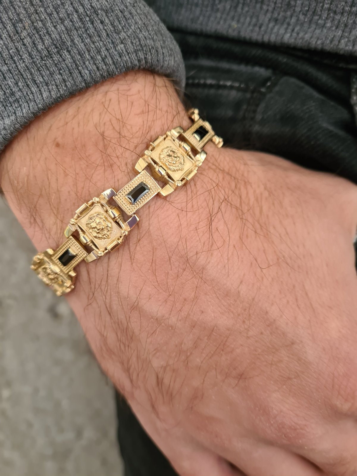 Bracelet with lions and green stones on men's wrist with gold plating