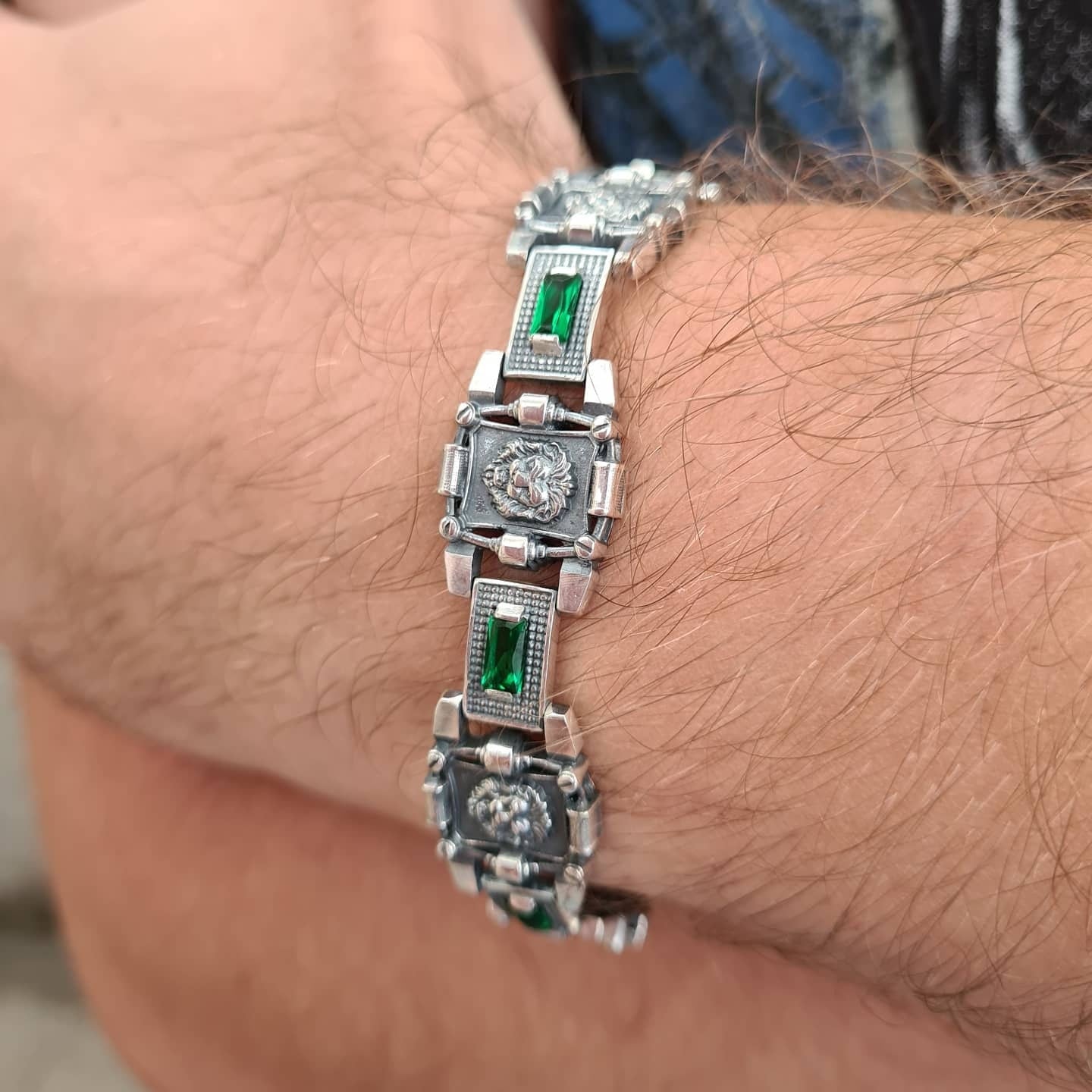 Close up of bracelet with lions and green stones on man's wrist