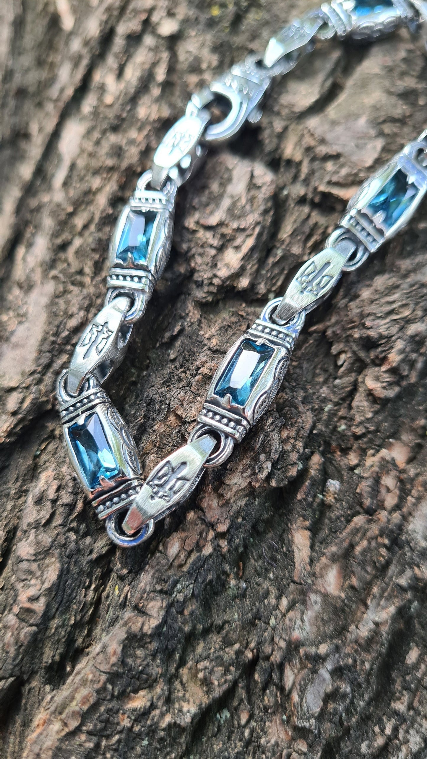 Vivid blue topaz stones set in sterling silver with engraved tryzub emblem. Handcrafted men's bracelet with symbolic Ukrainian design.


